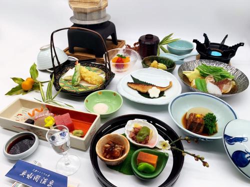 Okumizuma Onsen في Kaizuka: طاولة مليئة بأطباق الطعام والأطباق
