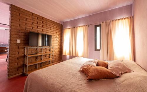 a bedroom with a large bed and a brick wall at Casa de Peter in Cafayate