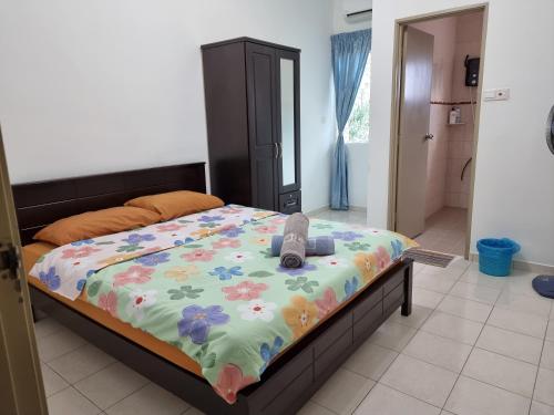 a bed with a colorful comforter with a pair of shoes on it at Sweethome Homestay Sandakan in Sandakan