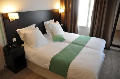 a bedroom with a large bed with white and green sheets at La Rose in Juliénas