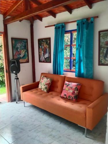 an orange couch in a living room with blue curtains at Génesis, un lugar para descansar y disfrutar in Santa Elena
