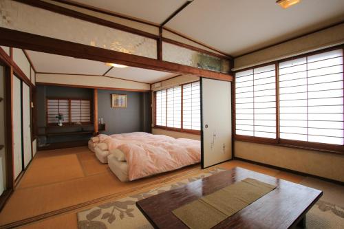 Schlafzimmer mit einem Bett, einem Tisch und Fenstern in der Unterkunft Ryokan Kibun in Tsuiki