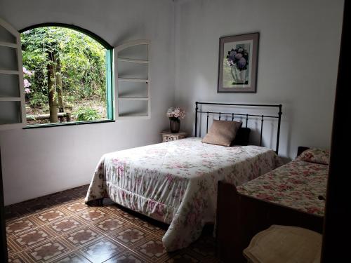 1 dormitorio con 2 camas y ventana en Sitio Natividade en Delfim Moreira