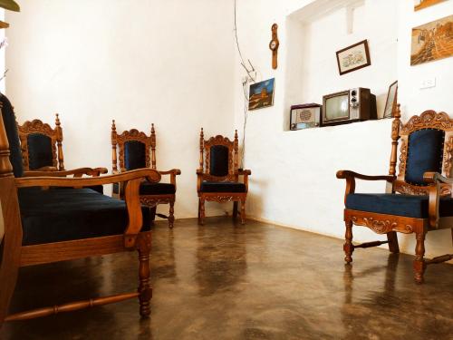 een kamer met vier antieke stoelen en een televisie bij Casa Orquidea Hostal Barichara in Barichara