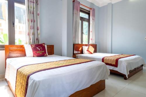 deux lits dans une chambre avec deux fenêtres dans l'établissement Heritage By Night, à Phong Nha