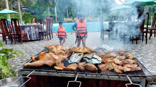 deux enfants debout à côté d'un grill avec des poulets et de la viande dans l'établissement Heritage By Night, à Phong Nha