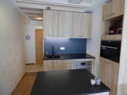 a kitchen with a black counter top and wooden cabinets at Appartement Le Grand-Bornand, 3 pièces, 6 personnes - FR-1-458-144 in Le Grand-Bornand