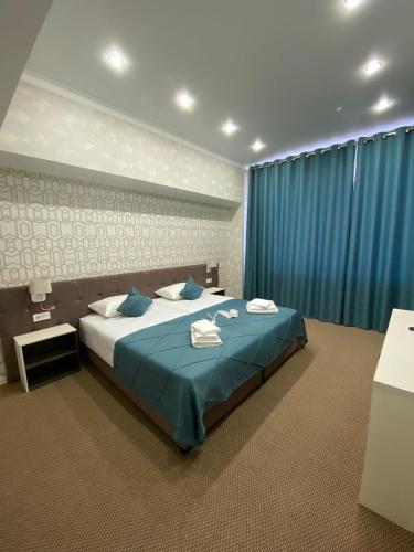 a bedroom with a large bed with blue curtains at De Marco Hotel in Kostanay
