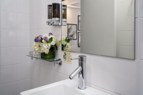 a bathroom with a sink and a mirror and flowers at Park Regis City Centre in Sydney