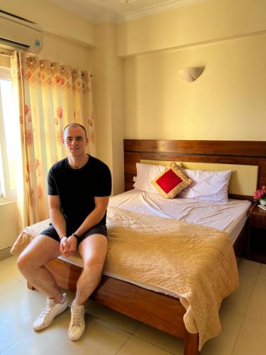 a man sitting on a bed in a room at Khách sạn NHẬT MINH Cửa Lò in Cửa Lò
