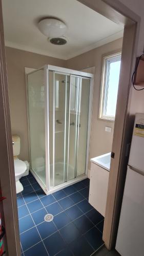 a bathroom with a glass shower and a toilet at Banana Coast Caravan Park in Coffs Harbour