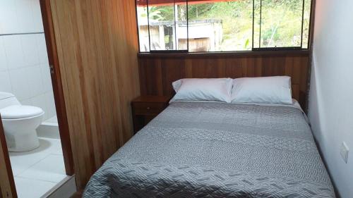 um pequeno quarto com uma cama e uma janela em Cabañas del bosque Don Efraín-La Merced em La Merced