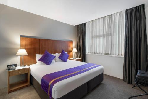 a hotel room with a large bed with blue pillows at Park Regis Griffin Suites in Melbourne