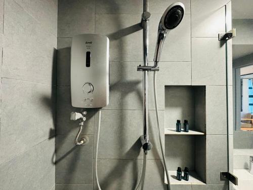 a shower in a bathroom with a hair dryer on the wall at Jesselton Quay - Suite 1 by Staycation Suites KK in Kota Kinabalu