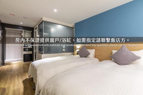 two beds in a room with a wall with writing at Hub Hotel Zhongli in Zhongli