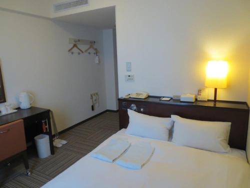 Una habitación de hotel con una cama con dos toallas. en Nest Hotel Kumamoto en Kumamoto