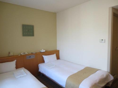 Habitación con 2 camas y reloj en la pared en Nest Hotel Kumamoto, en Kumamoto