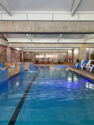a large swimming pool with blue water in a building at Sovereign Park Motor Inn in Ballarat