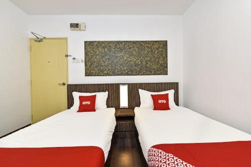 two beds with red pillows in a room at 4S Hotel in Muar