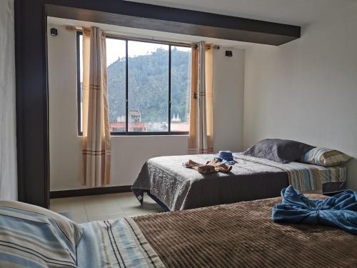 1 dormitorio con 2 camas y ventana en GIGAHOUSE, en Baños