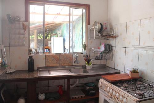 a kitchen with a sink and a stove and a window at Hospedagem Caminho das Águas in Paraty