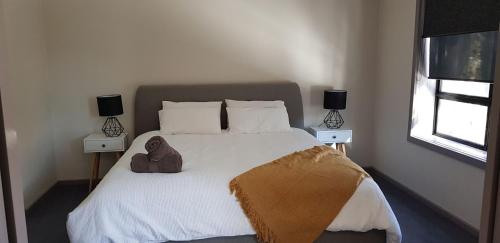 a bedroom with a large white bed with two lamps at Peak 105 in Mount Buller