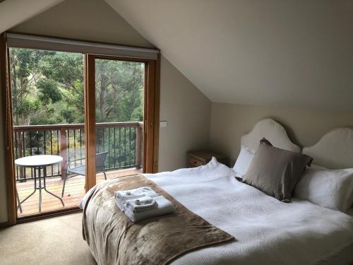 a bedroom with a large bed and a balcony at Day Dream Cottage in Merrijig