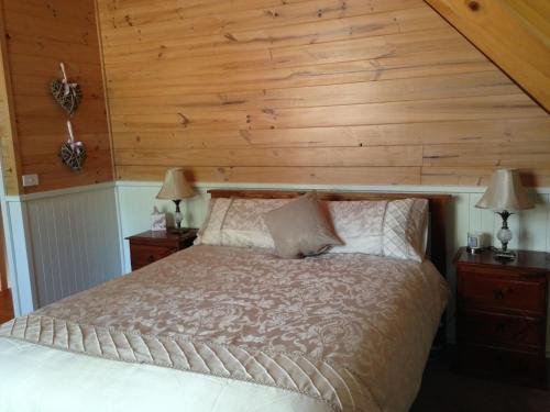 1 dormitorio con 1 cama con pared de madera en Kookas Cottage en Merrijig