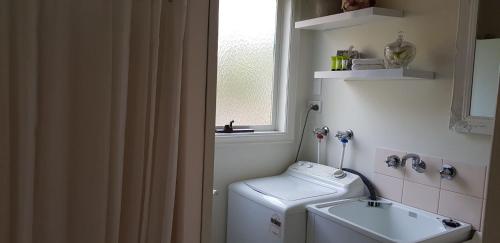 a small bathroom with a washing machine and a window at Kookas Cottage in Merrijig