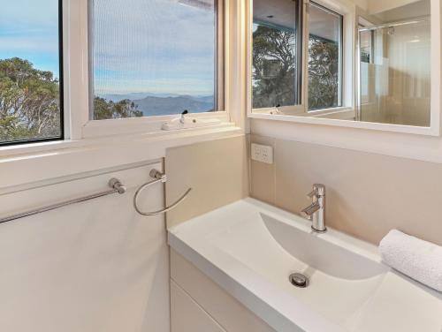 a white bathroom with a sink and two windows at SKI View 4 in Mount Buller