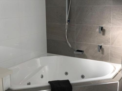 een badkamer met een wit bad en een douche bij Twin Towers 701A in Mount Buller