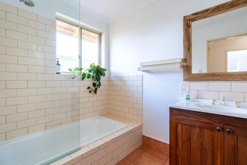 a bathroom with a tub and a sink and a mirror at Double J's in Margaret River Town