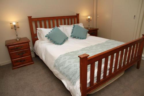 a bedroom with a wooden bed with blue pillows at Woollybutt in Merrijig