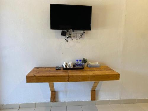 een houten tafel met een flatscreen-tv aan de muur bij Bayu Cenang Inn in Pantai Cenang