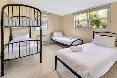 a bedroom with two bunk beds and two windows at Elouera in Mansfield