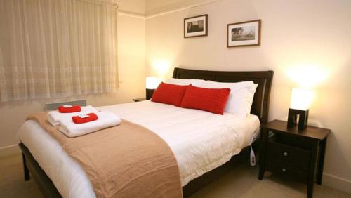 a bedroom with a bed with two red pillows on it at Elouera in Mansfield