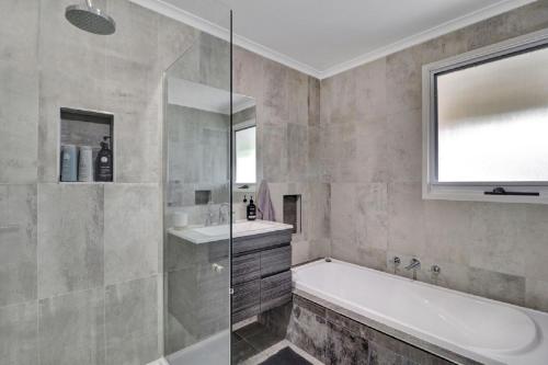 een badkamer met een bad, een wastafel en een spiegel bij Katta Cottage in Mansfield