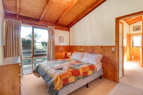 een slaapkamer met een bed en een groot raam bij 41Alpine Ridge Drive in Merrijig