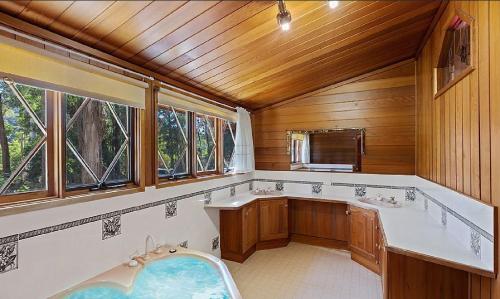 baño con bañera y 2 lavabos y ventanas en Lumi Talo en Merrijig