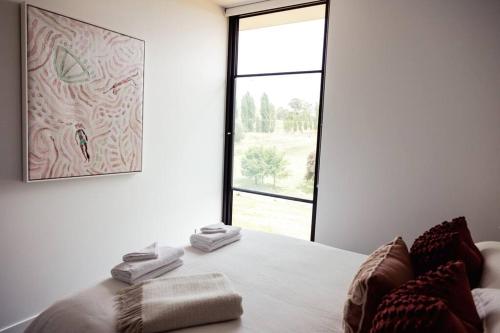 a white room with a bed with a window at The Horned Cow - award winning luxe semi-rural house 10mins from Orange in Lucknow