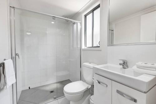 a bathroom with a toilet and a shower and a sink at MARJ12- Stylish and Spacious in Mooloolaba