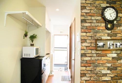 uma cozinha com uma parede de tijolos e um relógio na parede em 優宿 Kitakoiwa em Tóquio