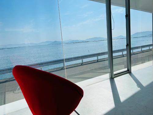 a red chair sitting in front of a window at Mare di Miyajima マーレ ディ ミヤジマ in Miyajima