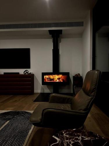a living room with a leather chair and a fireplace at The Horned Cow - award winning luxe semi-rural house 10mins from Orange in Lucknow