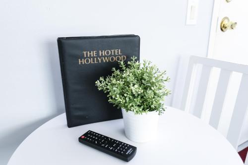 a book and a plant on a table with a remote control at The Hotel Hollywood in Los Angeles