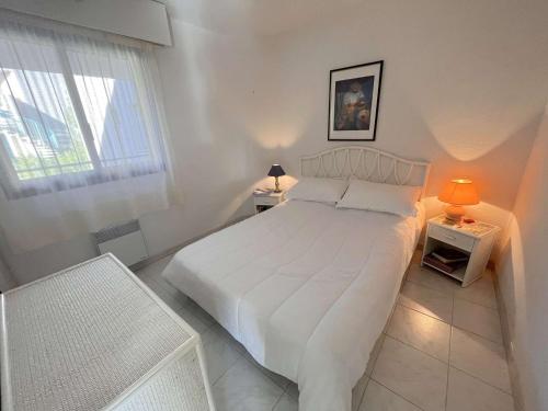 een witte slaapkamer met een wit bed en een raam bij Appartement Cavalaire-sur-Mer, 2 pièces, 2 personnes - FR-1-226B-139 in Cavalaire-sur-Mer