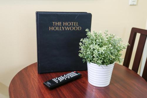 a book and a remote control on a table with a plant at The Hotel Hollywood in Los Angeles