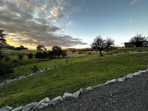 a grassy hill with a stone wall in a field at The Horned Cow - award winning luxe semi-rural house 10mins from Orange in Lucknow