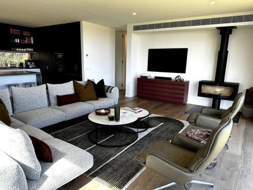 a living room with a couch and a table and a tv at The Horned Cow - award winning luxe semi-rural house 10mins from Orange in Lucknow