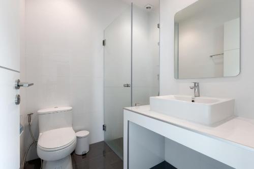 a white bathroom with a toilet and a sink at Orchid Paradise Homes OPV422 in Hua Hin